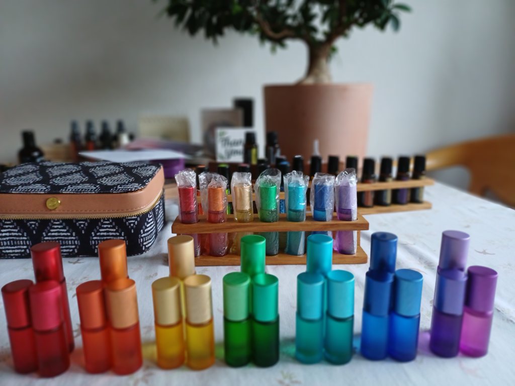 Sieben Chakra-Essenzen in Regenbogenfarben auf einem Holzständer