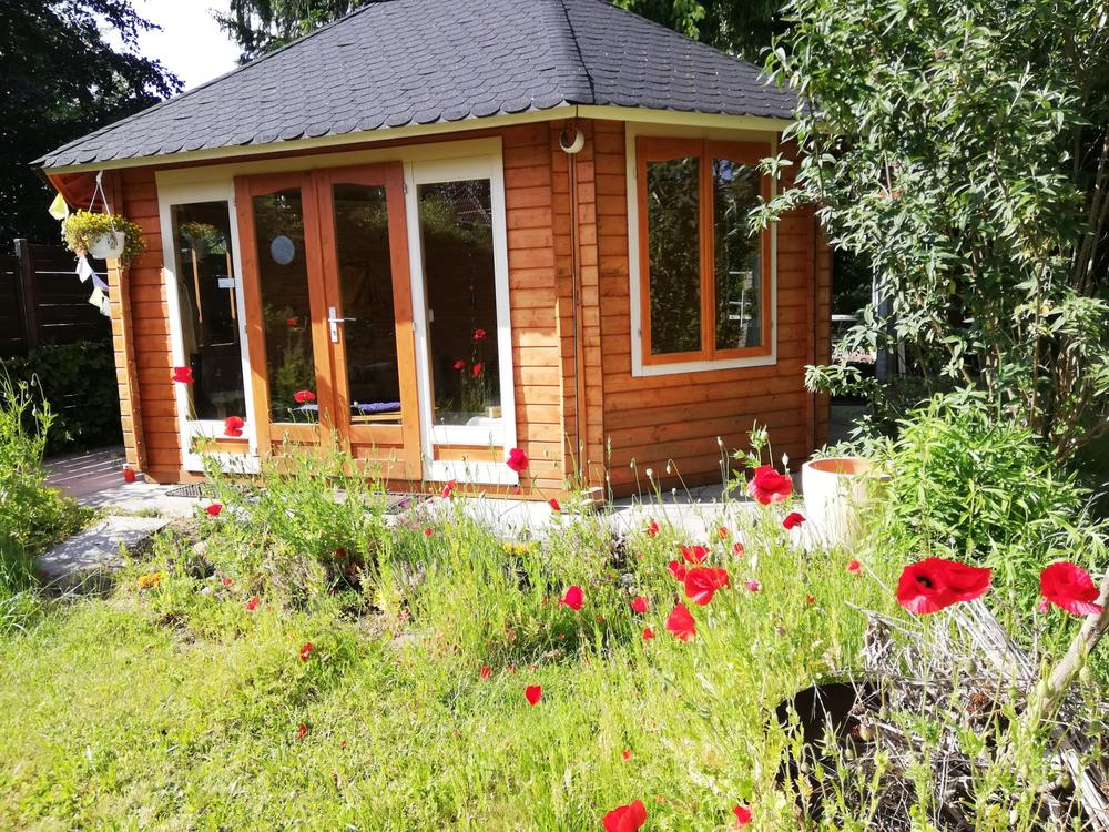 Holzpavillon im Garten, davor roter Mohn