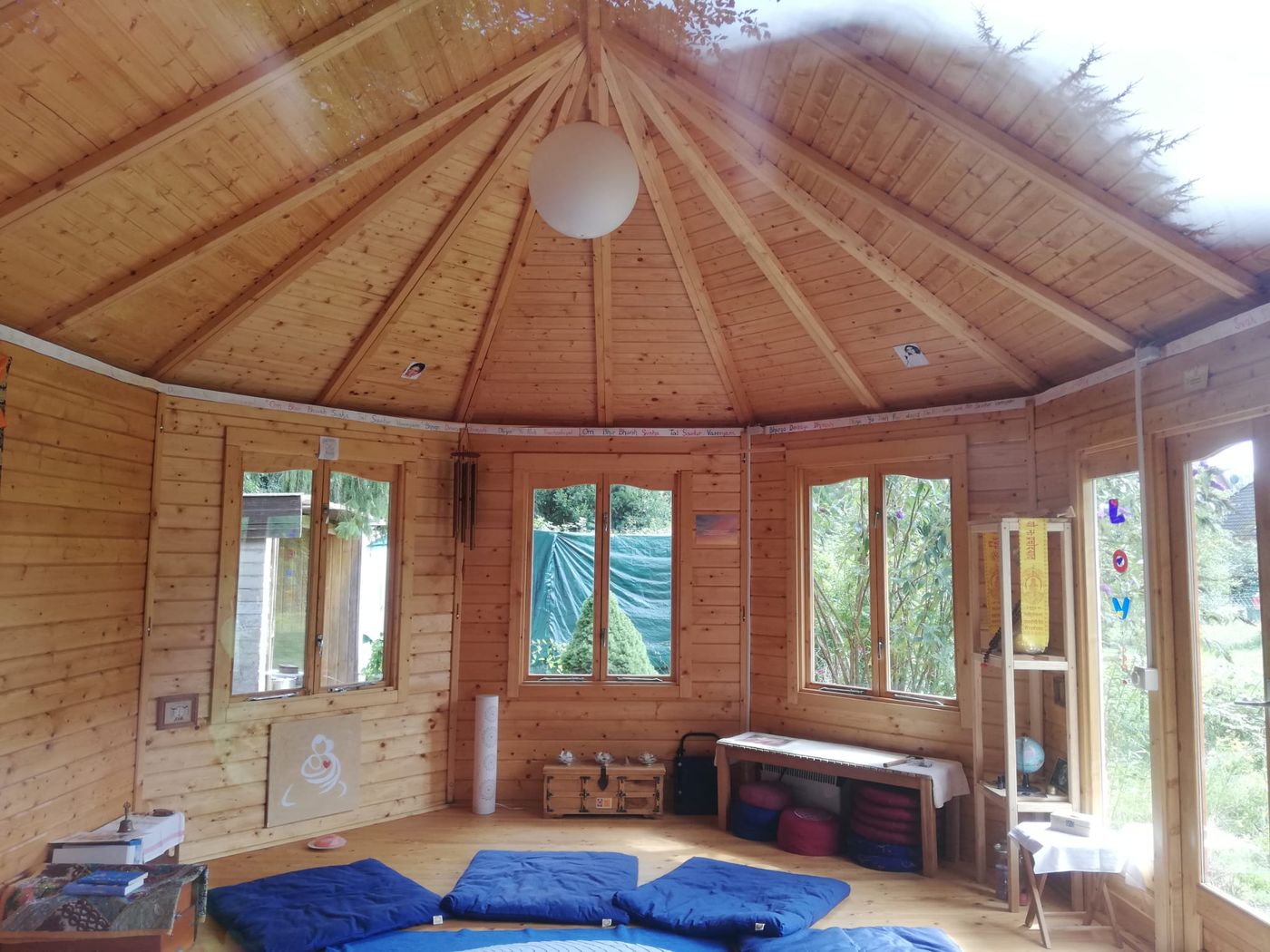 Achteckiger Holzpavillon von innen, blaue Meditationsmatten auf dem Holzboden